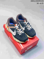 Pair of navy Nike Zoom Vomero 5 sneakers displayed on a red shoebox, showing white laces, white Swoosh branding, and off-white midsoles.