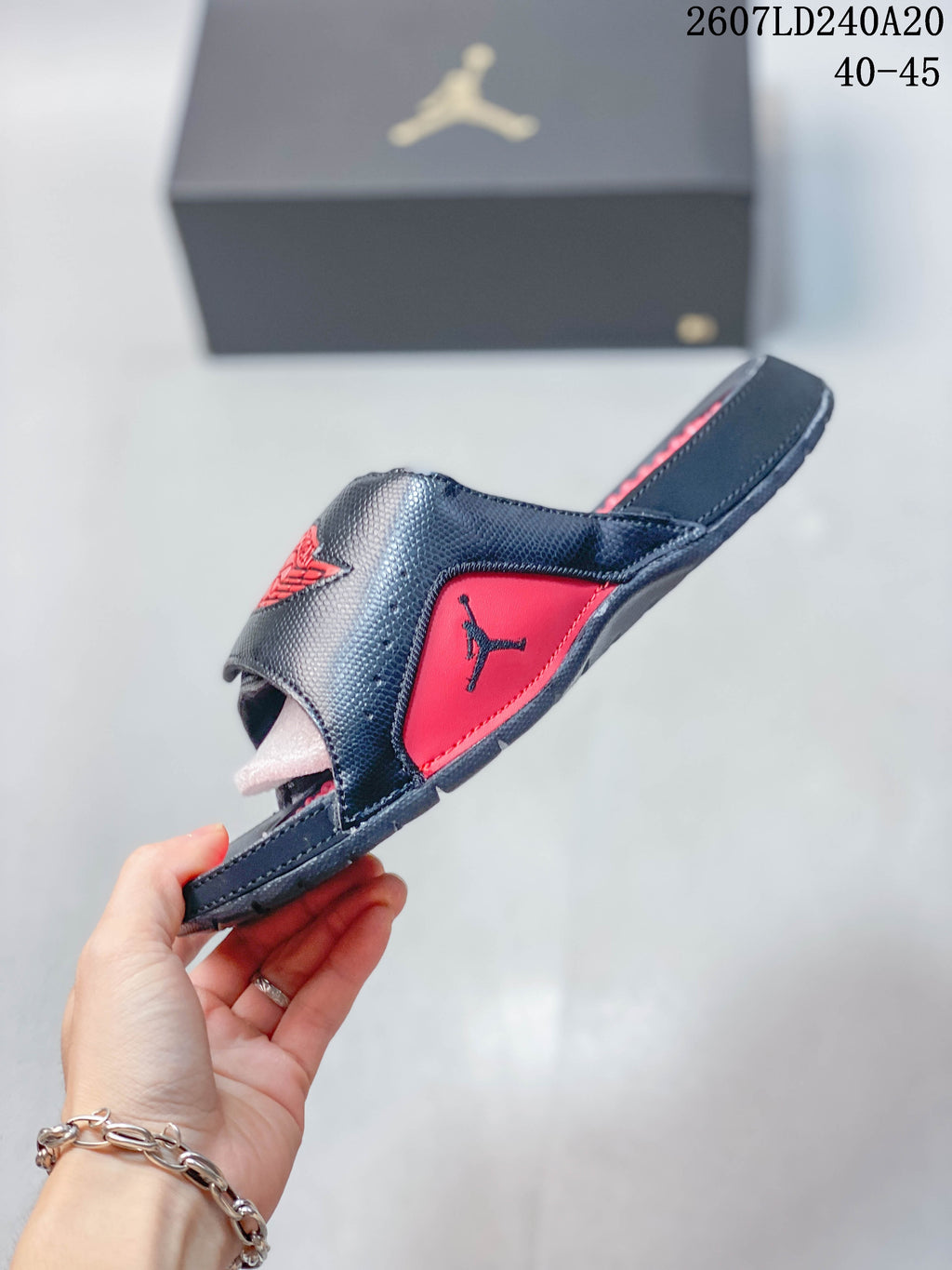 Side profile of the black and red slide showing the raised upper, open-toe construction, and textured outsole edge.