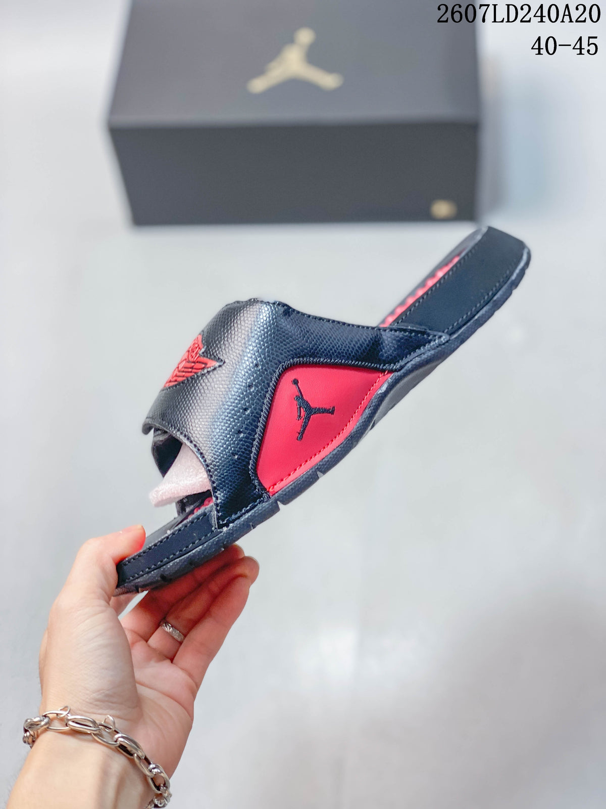Side profile of the black and red slide showing the raised upper, open-toe construction, and textured outsole edge.
