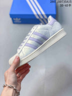Side profile showing the white upper, lavender three stripes, lace-up design, and rubber sole.