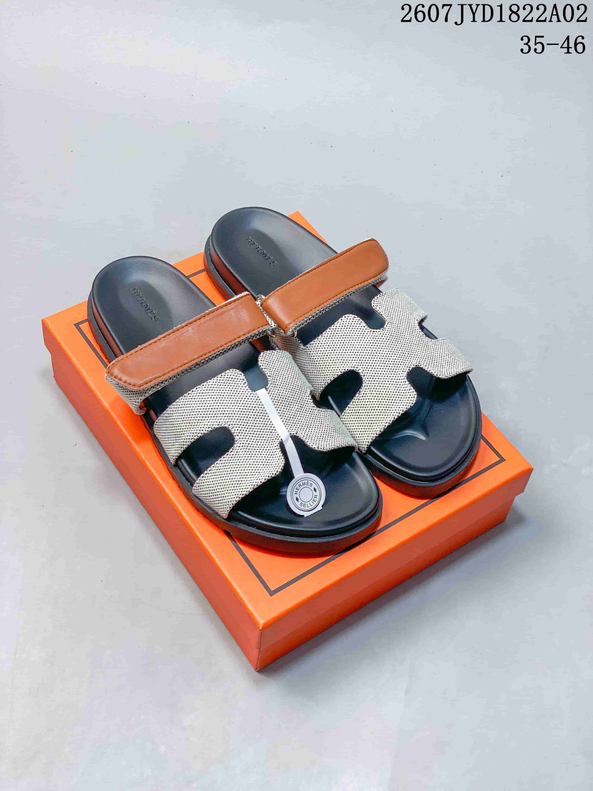 Pair of Hermès Kazimir slide sandals with tan strap accents and light patterned uppers.