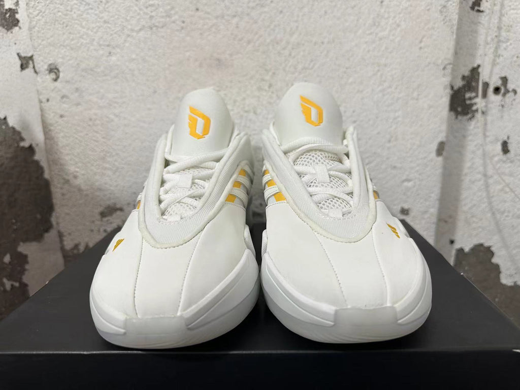 Front view of white Adidas Dame 9 basketball shoes with yellow tongue logos