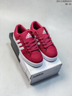 Pair of red adidas low-top sneakers with white stripes displayed on an adidas shoe box.