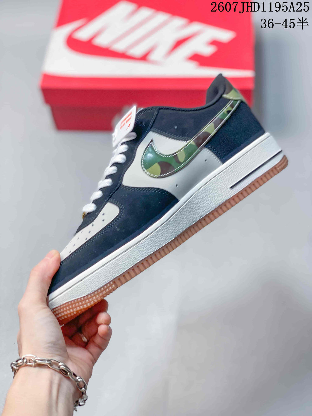 Side view highlighting the navy and white upper, green camouflage-patterned Swoosh, white midsole, and gum outsole.