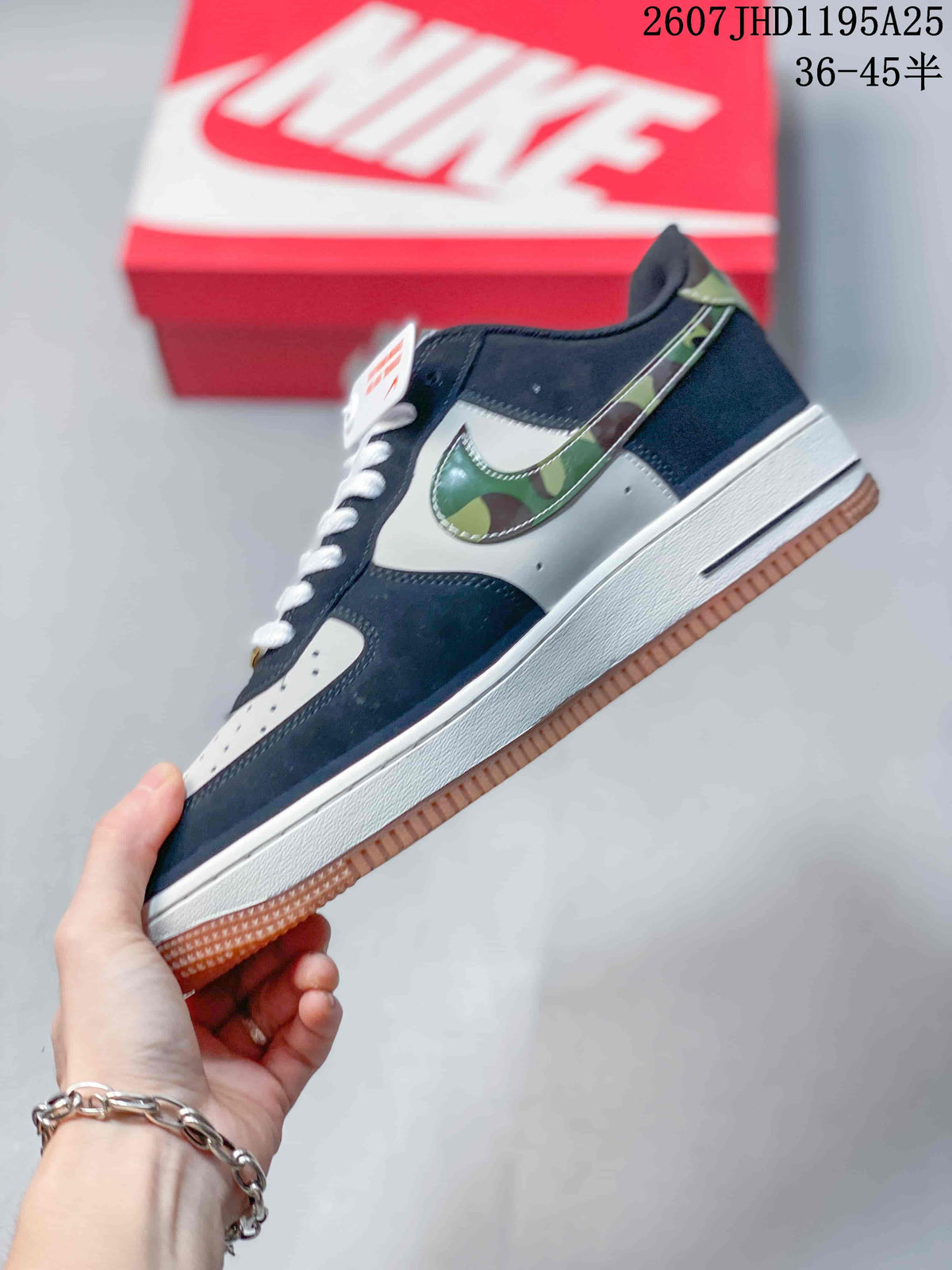Side view highlighting the navy and white upper, green camouflage-patterned Swoosh, white midsole, and gum outsole.
