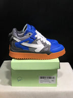 Side view of the sneakers on a shoebox, showing the large white arrow detail, layered panels, and gum-colored outsole.