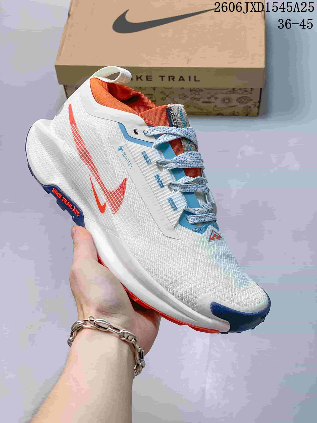 Angled side view of the white Nike trail shoe with orange and blue accents