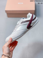 Side profile of the white low-top sneaker showing burgundy side accents, tonal paneling, lace closure, and a low white outsole.