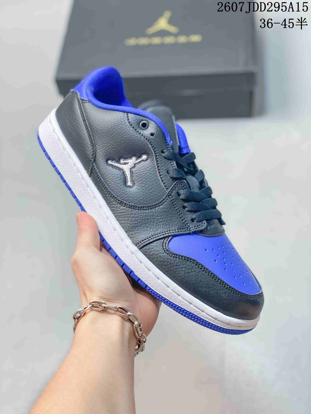 Angled side view of the black and blue low-top sneaker showing the Jordan logo, blue toe box, white midsole, and blue outsole.