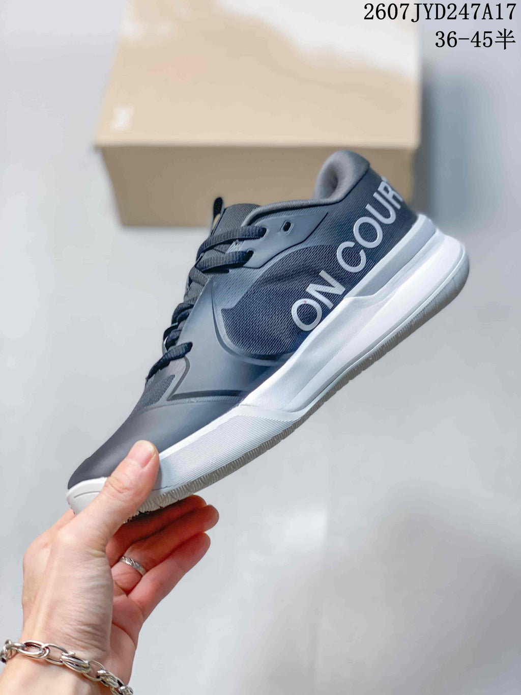 Side view showing the dark gray upper, large On branding, white midsole, and pink accent.