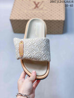 Top view showing the broad monogram-patterned strap, light footbed, and decorative side plaque.