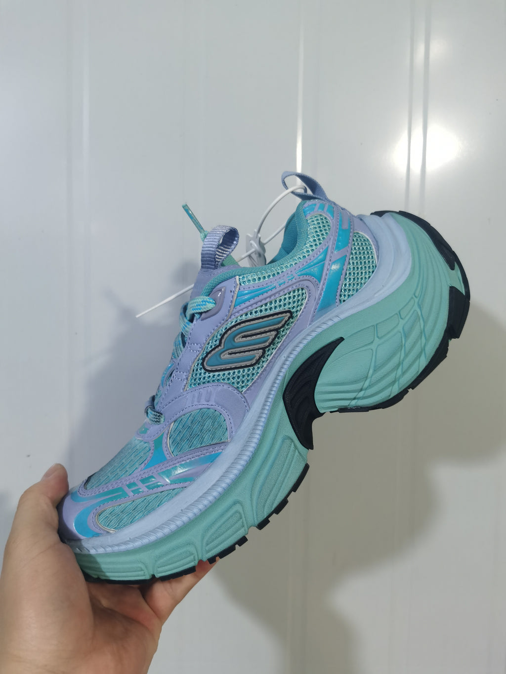 Side view of the blue mix Skechers 4410 sneaker showing the layered upper, lace area, mesh sections, and black outsole details.