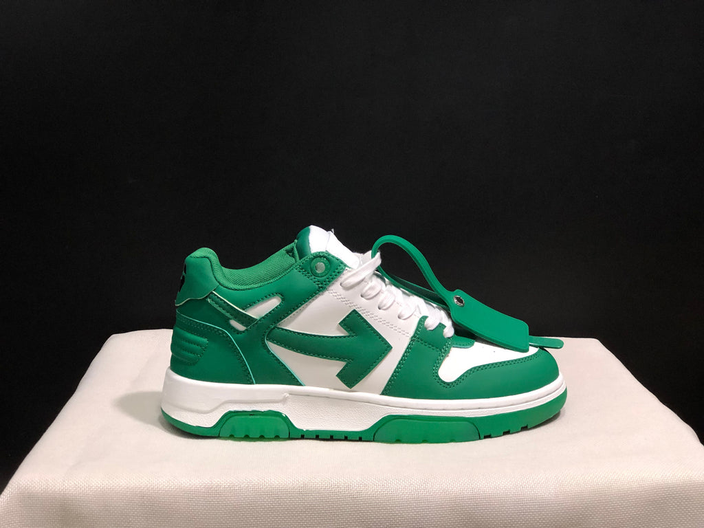 Side view of one green and white sneaker with a green tag accessory placed across the laces.