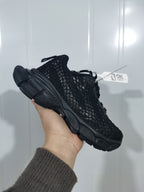 Side view of a black fishnet-style sneaker showing the layered upper, padded collar, and textured outsole.