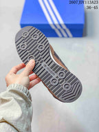Close view of the dark patterned outsole of a brown adidas sneaker, showing circular tread details and adidas branding.