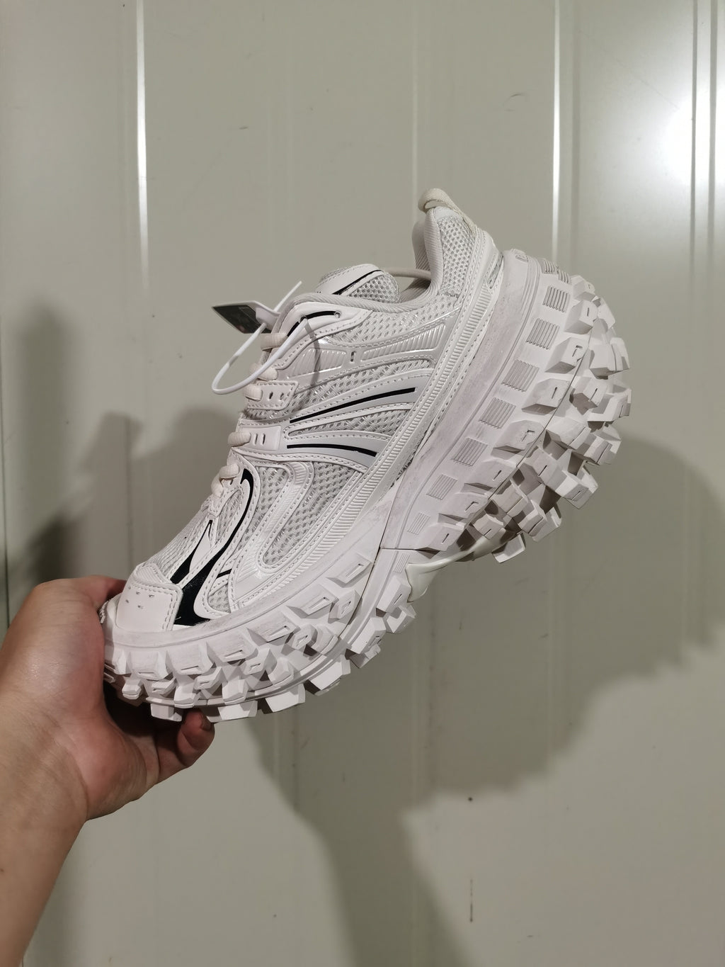 Angled view of the white and black sneaker showing the mesh upper, side overlays, and textured outsole.