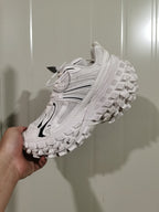 Angled view of the white and black sneaker showing the mesh upper, side overlays, and textured outsole.