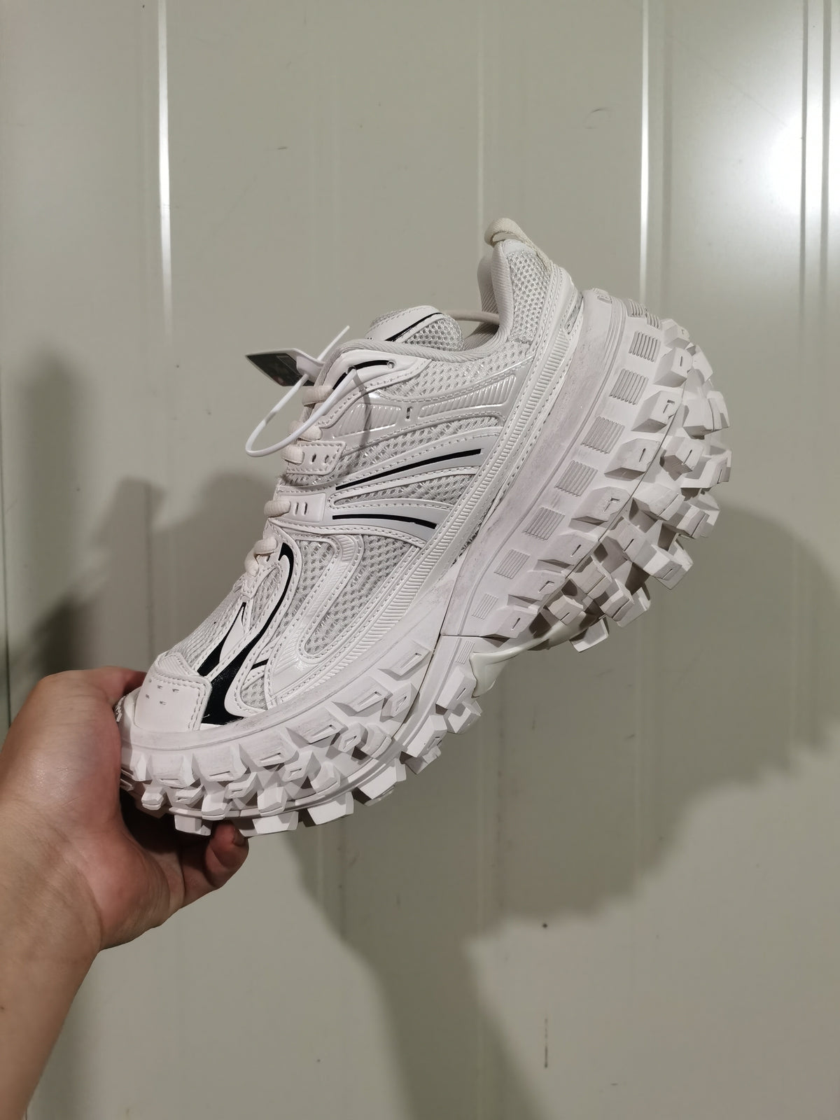Angled view of the white and black sneaker showing the mesh upper, side overlays, and textured outsole.