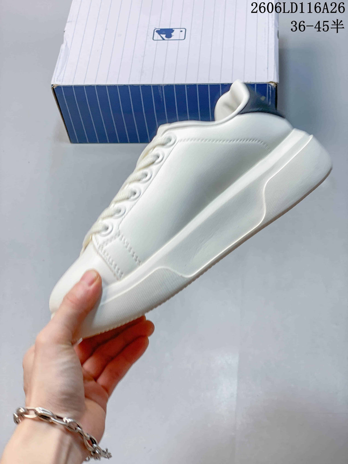 Side profile of the white low-top sneaker showing the smooth upper, lace eyelets, raised sole, and dark heel detail.