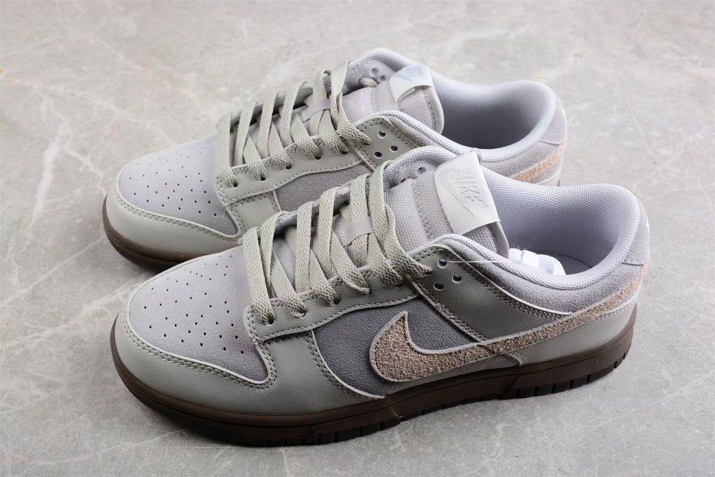 Pair of light gray and off-white Nike SB low-top sneakers with beige Swooshes and dark brown outsoles.