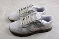 Pair of light gray and off-white Nike SB low-top sneakers with beige Swooshes and dark brown outsoles.