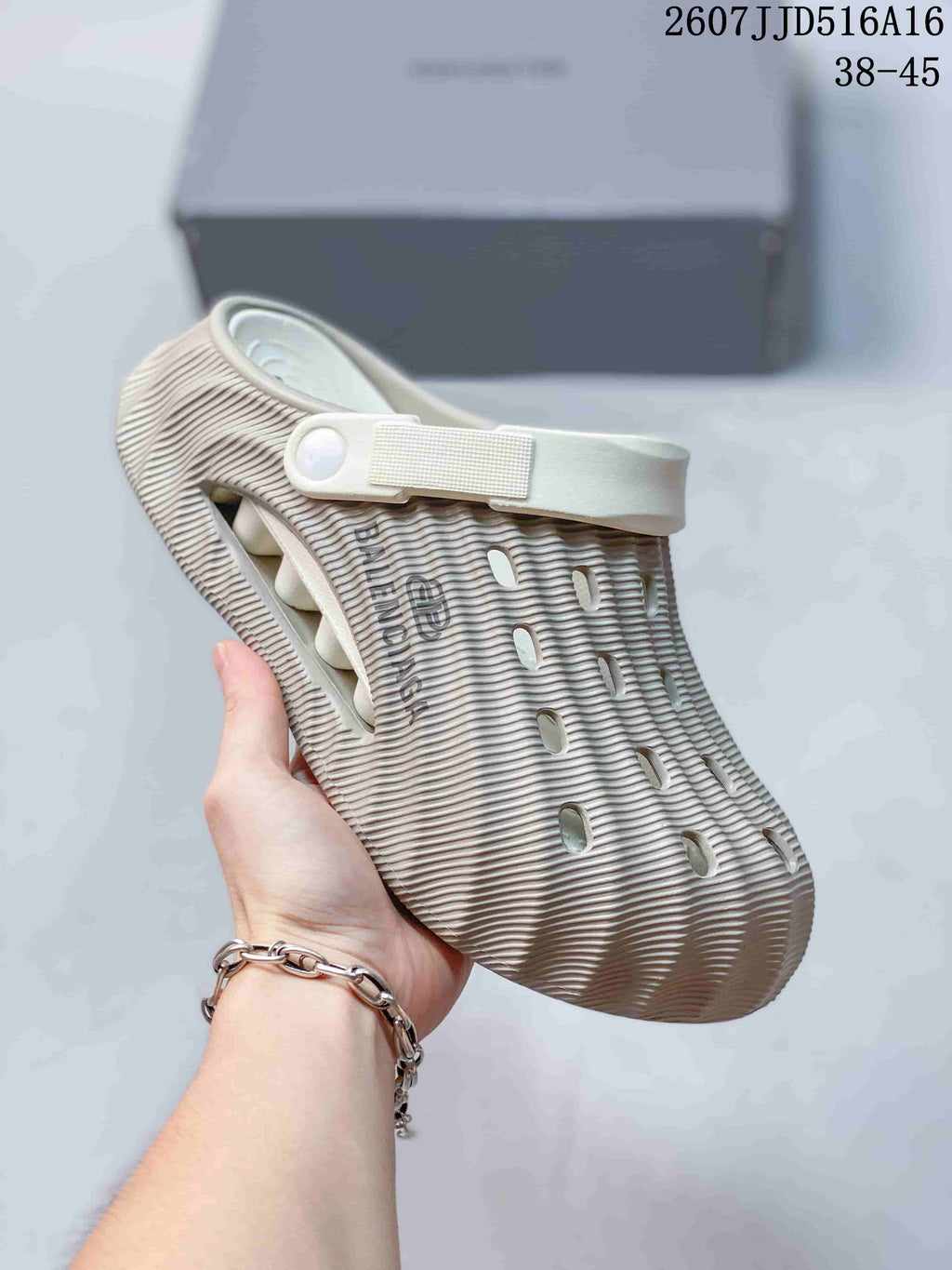 Side view of a cream ribbed clog sandal showing the adjustable heel strap, ventilation openings, closed toe, and textured upper.