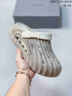 Side view of a cream ribbed clog sandal showing the adjustable heel strap, ventilation openings, closed toe, and textured upper.