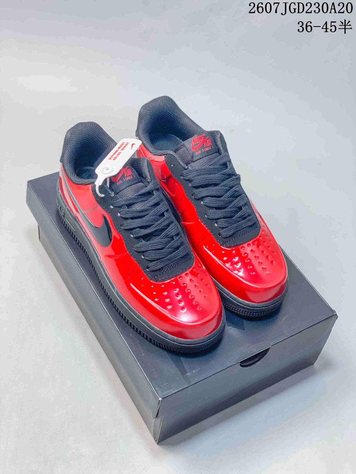 Pair of red and black low-top Nike Air Force 1 sneakers displayed on a black shoebox; image text shows style code 2607TGD230A20 and size range 36–45 with half sizes.