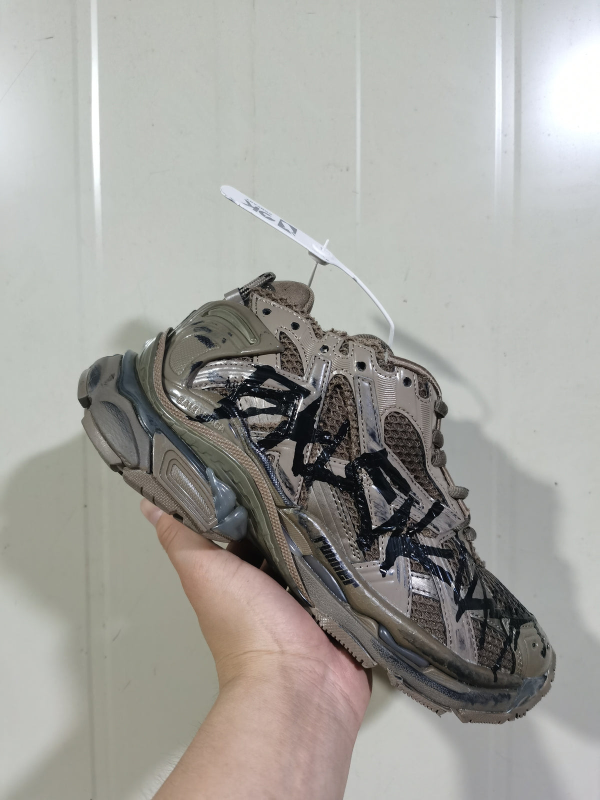 Close angled view showing the layered panels, mesh sections, tonal laces, and black detailing on the Balenciaga Runner 2010 sneaker.