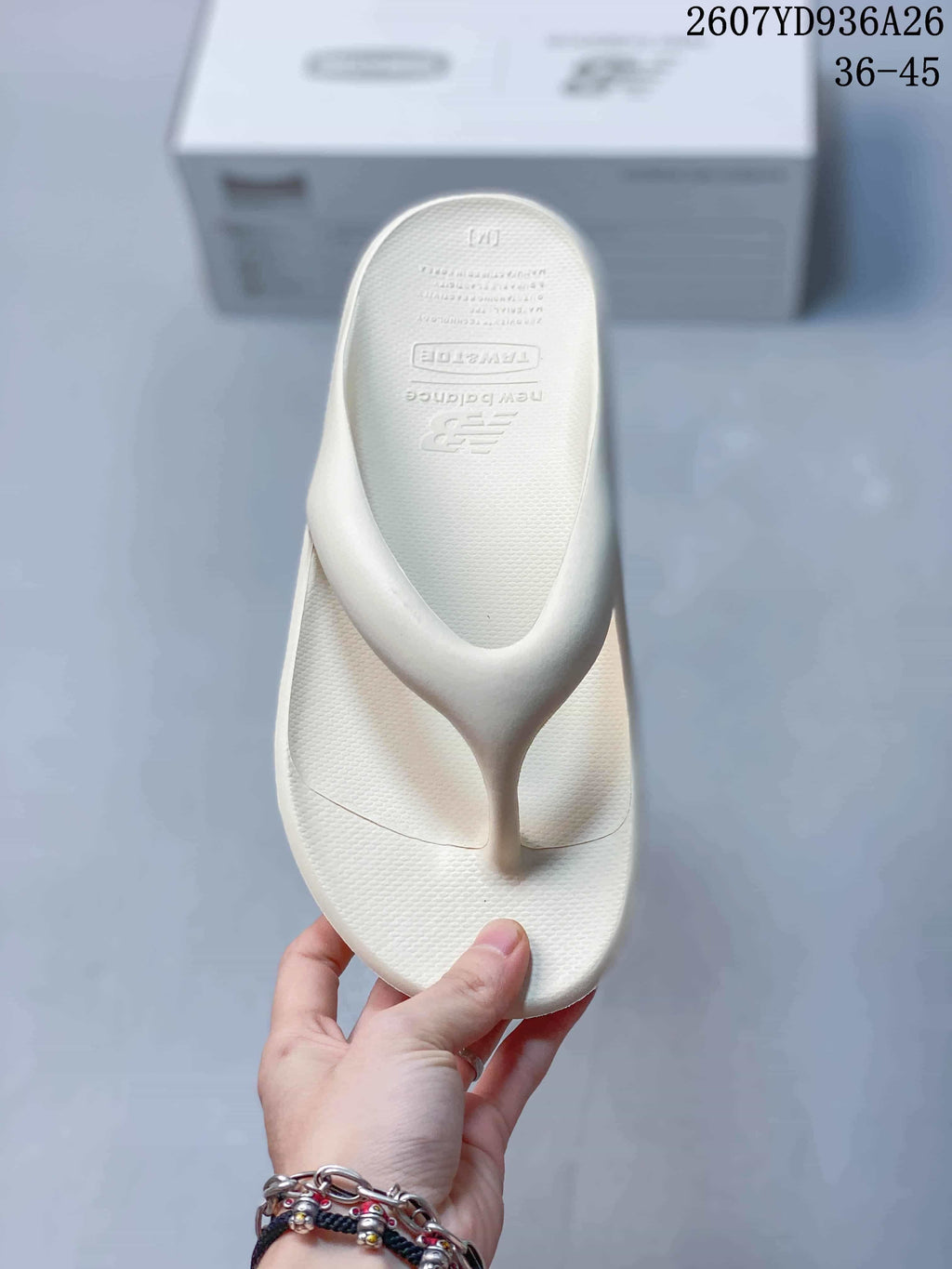 Top view of an off-white New Balance flip-flop sandal showing the textured footbed and embossed branding.