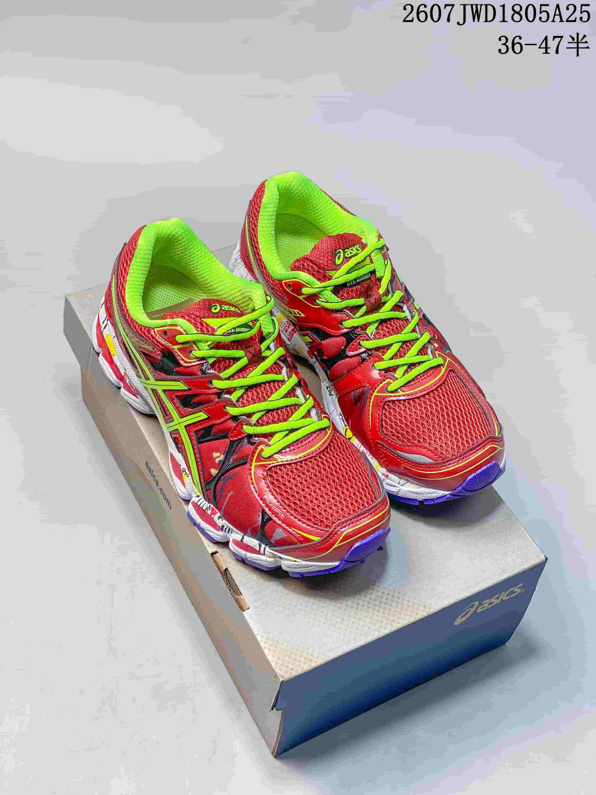 Pair of red and neon green ASICS Gel-Nimbus 16 shoes displayed on a branded shoebox.