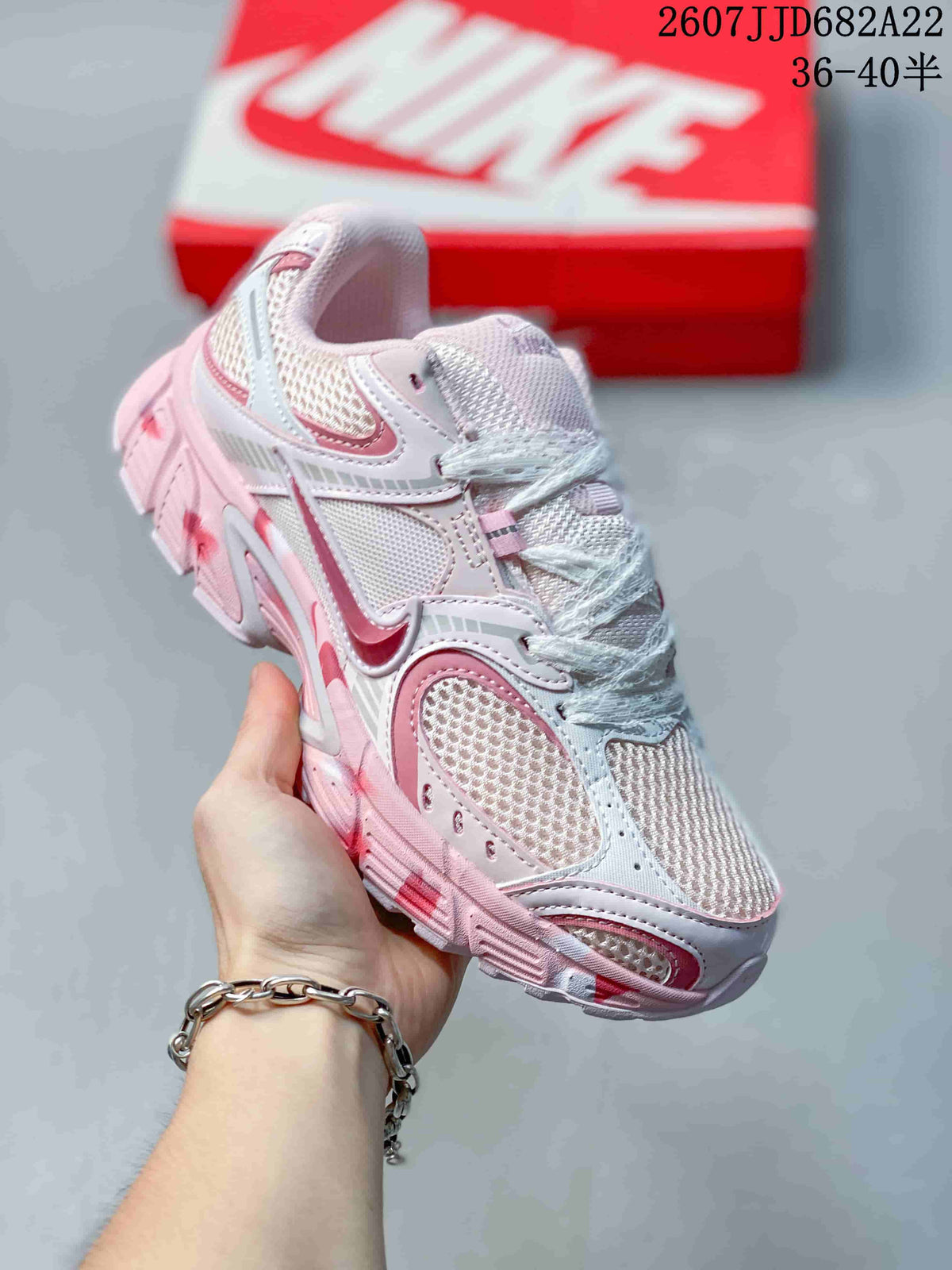 Angled close view of the white and pink sneaker with layered side panels and a chunky outsole.