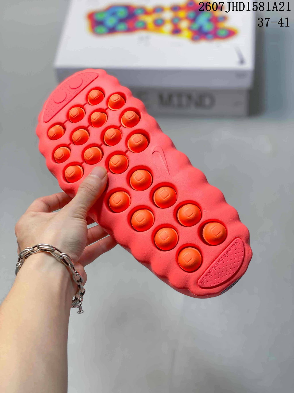Close view of the coral slide outsole showing raised circular details and a molded tread pattern.
