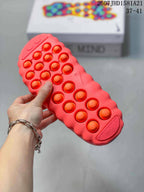 Close view of the coral slide outsole showing raised circular details and a molded tread pattern.