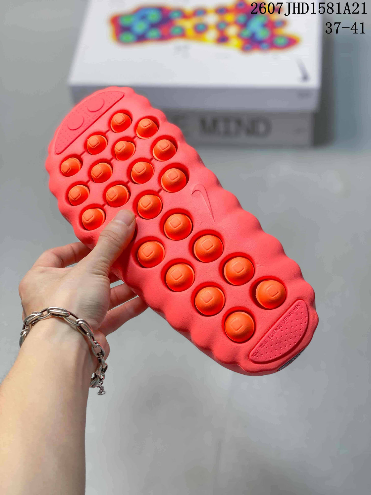 Close view of the coral slide outsole showing raised circular details and a molded tread pattern.