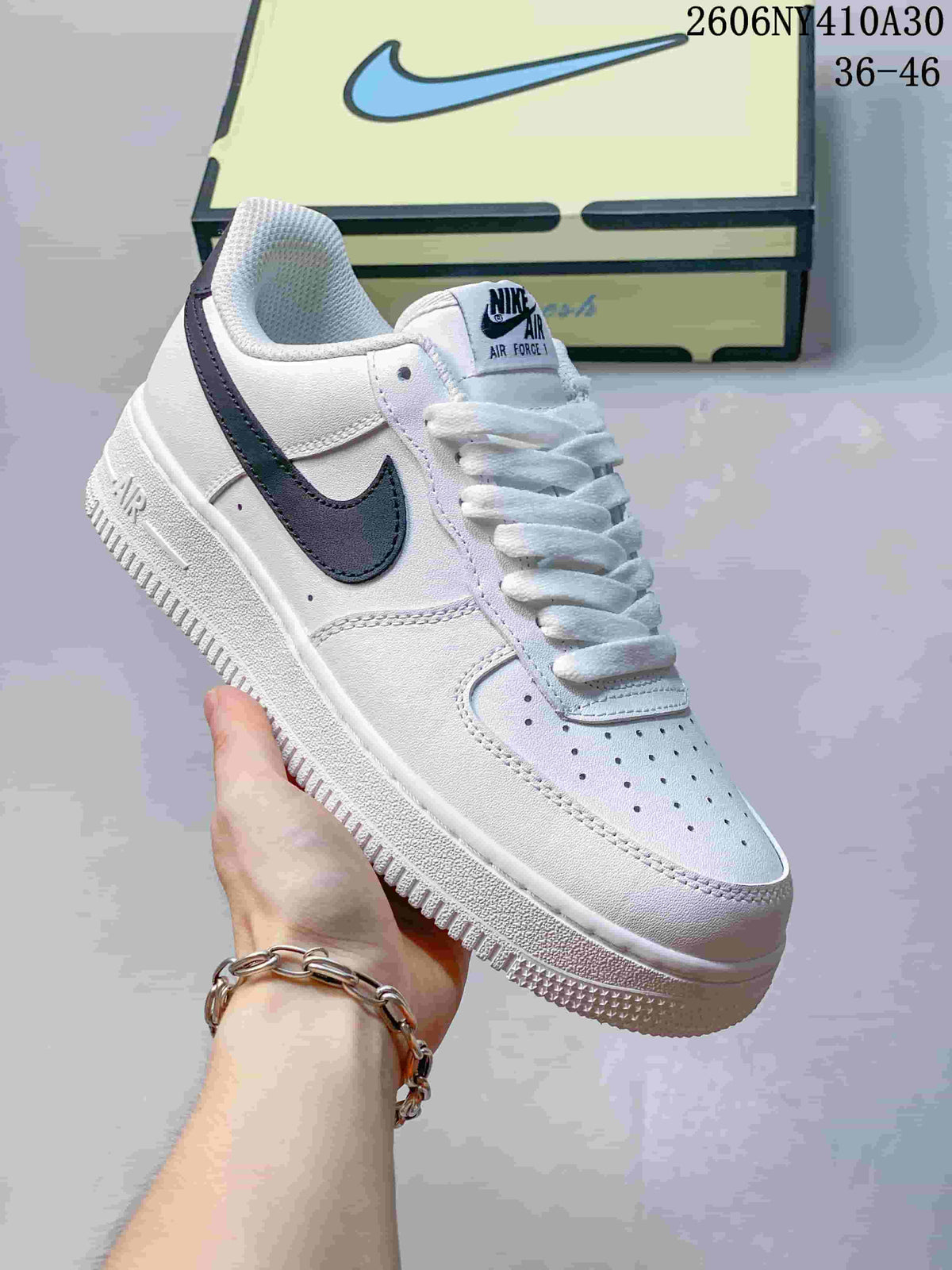 Angled view of the white sneaker with navy accents and a perforated toe