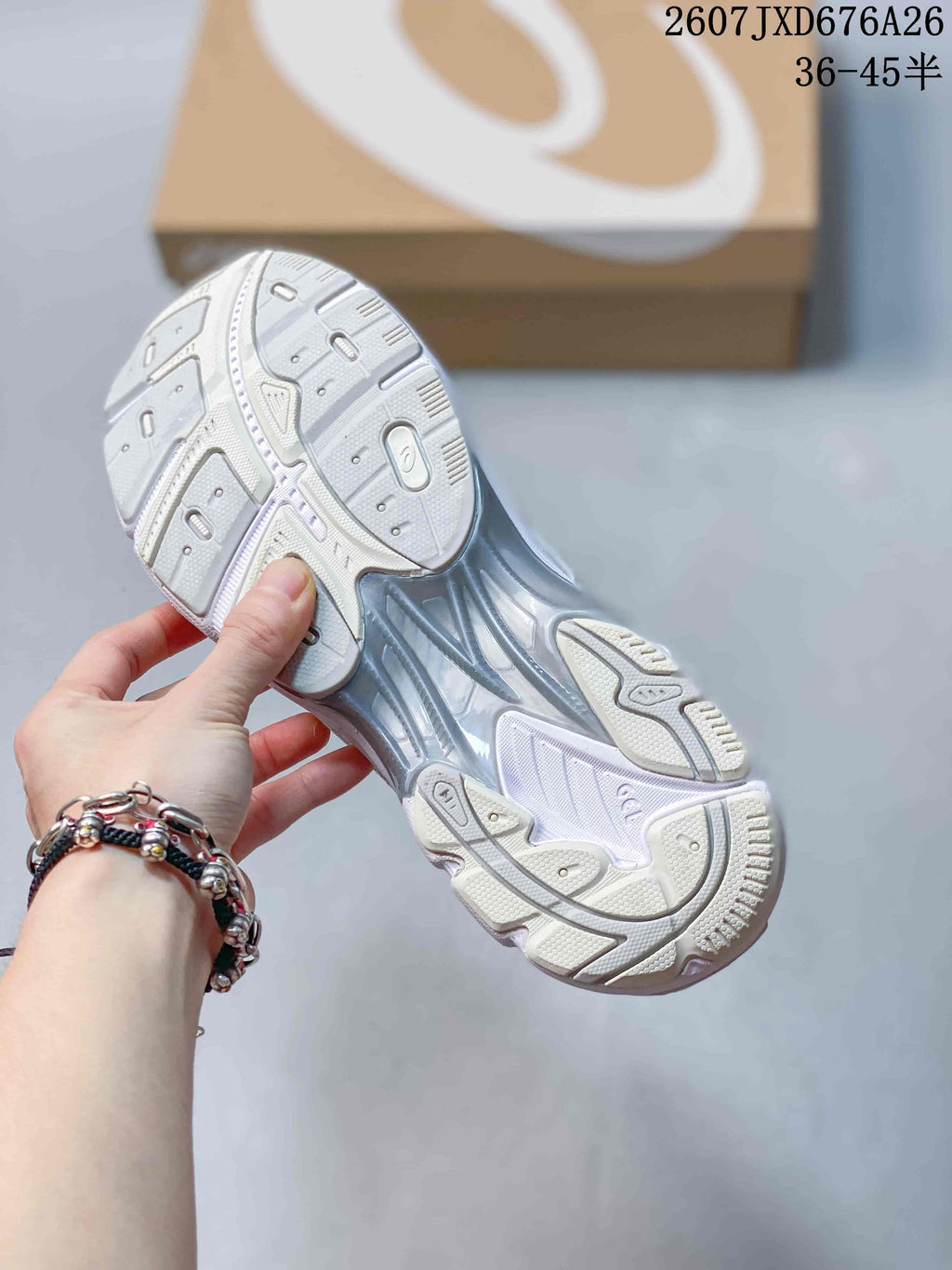 Underside view of the white and silver sneaker showing the segmented outsole tread and translucent central section.