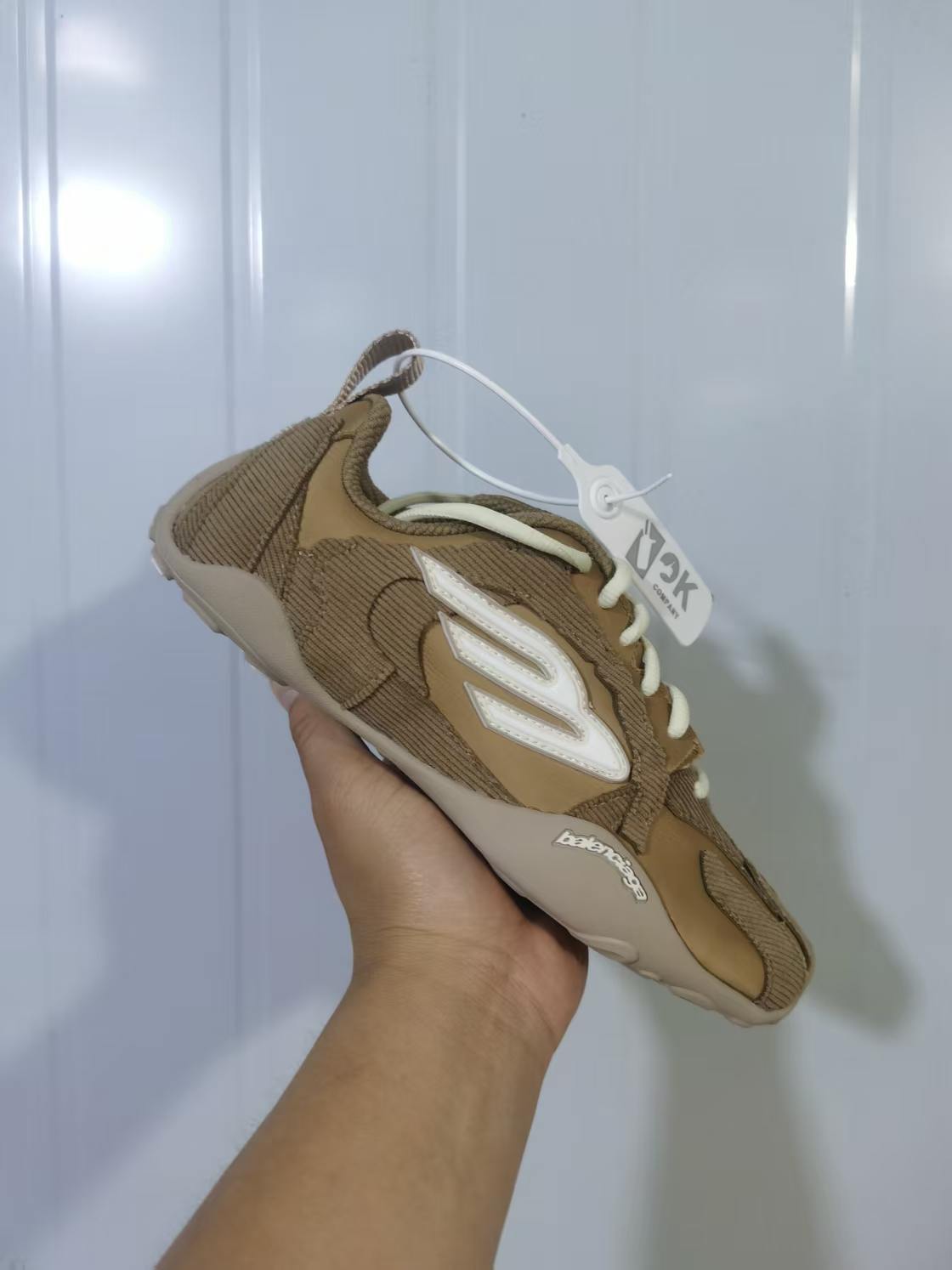 Angled top view showing the beige and white upper, contrasting laces, side branding, and layered panels.