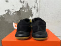 Rear view of black and gold Nike basketball sneakers on an orange box