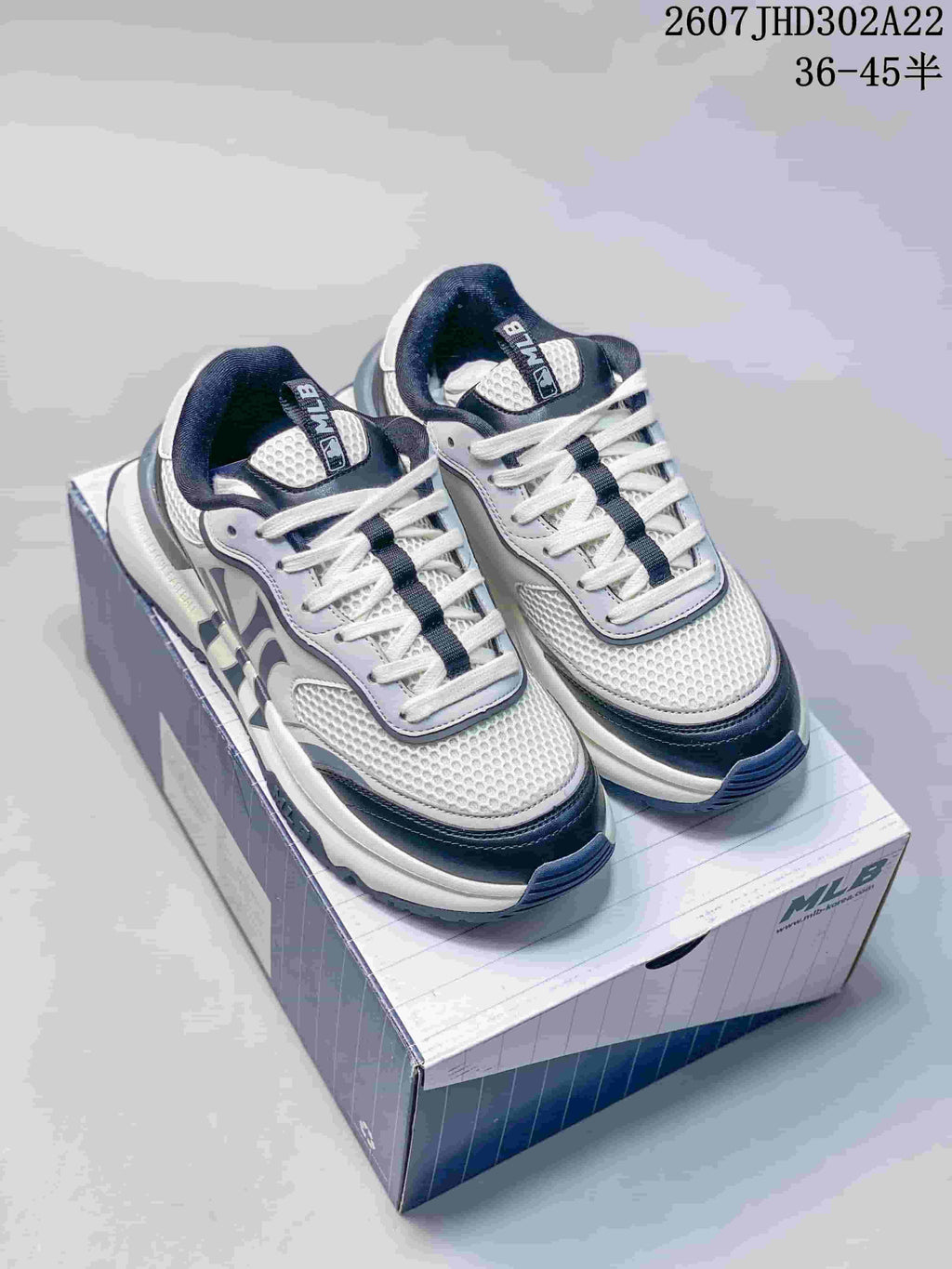 White and navy MLB Chunky Runner sneakers displayed on their box, showing the layered upper, mesh-look panels, and thick sole.