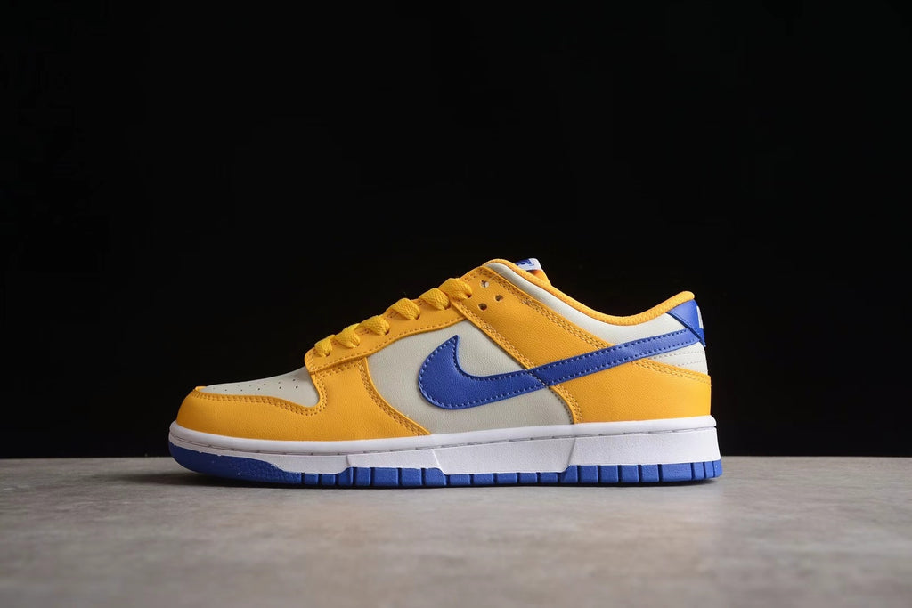 Side profile showing the wheat gold upper, light-colored side panel, blue Swoosh, white midsole, and blue outsole.
