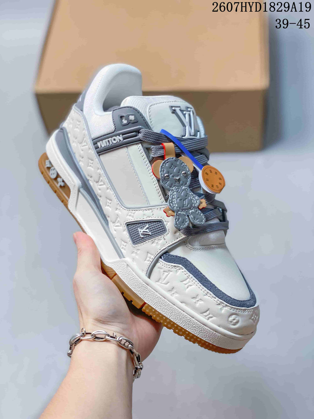 Angled side view of the white and gray Louis Vuitton sneaker showing the embossed upper panels, layered construction, gray trim, and gum outsole.