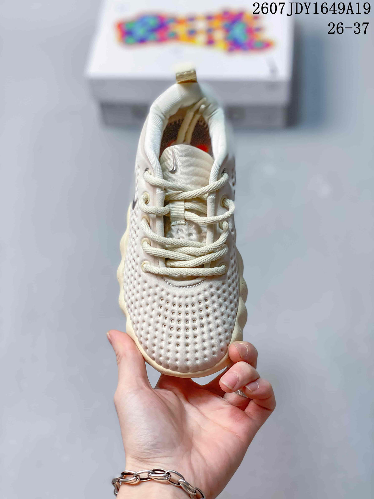 Front view of the cream sneaker showing the perforated toe box, tongue, and cream laces.