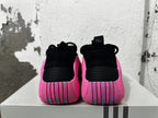 Rear view of black sneakers with bright pink heels and ribbed heel details.