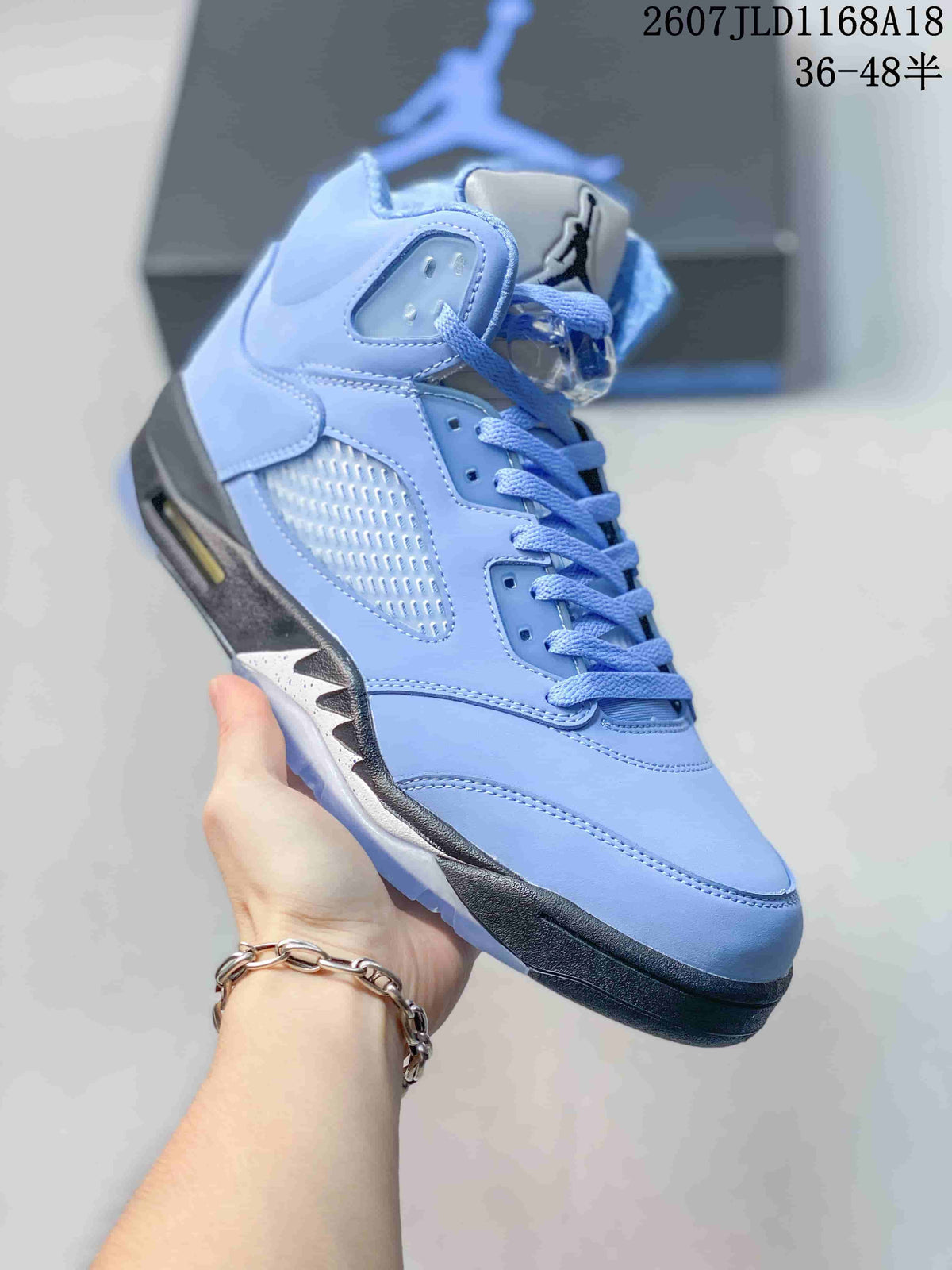 Angled side view highlighting the light blue upper, side mesh panel, padded collar, lace-up front and dark outsole.