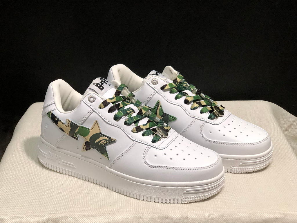 Three-quarter front view of the pair highlighting the white uppers, camouflage side panels, and textured soles.