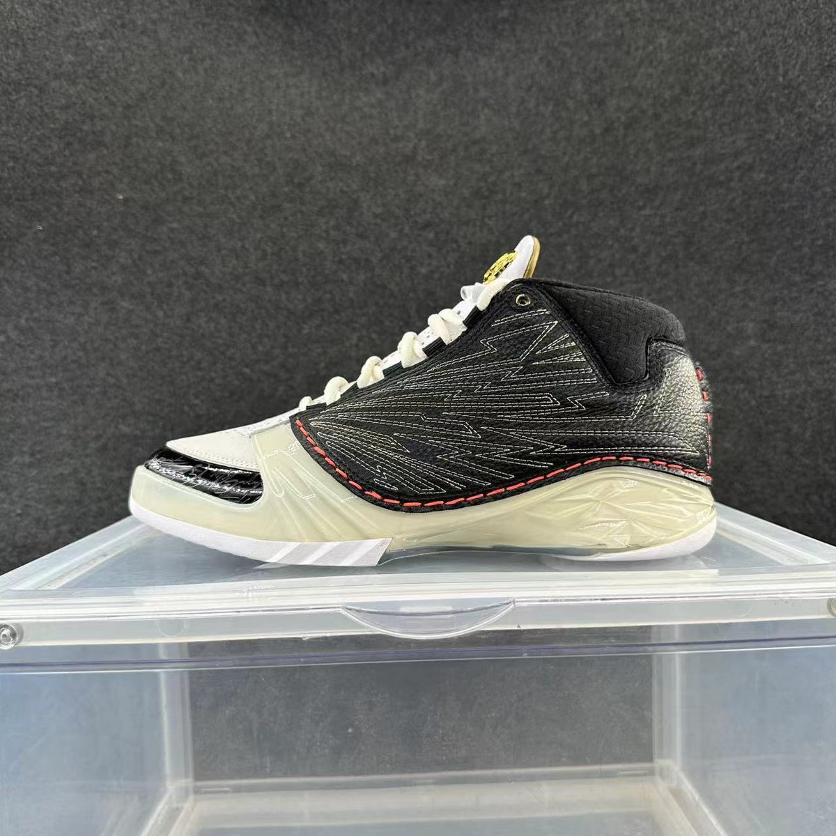 Side view of a black and white high-top basketball sneaker with white laces, red stitching, and translucent-looking sole details.