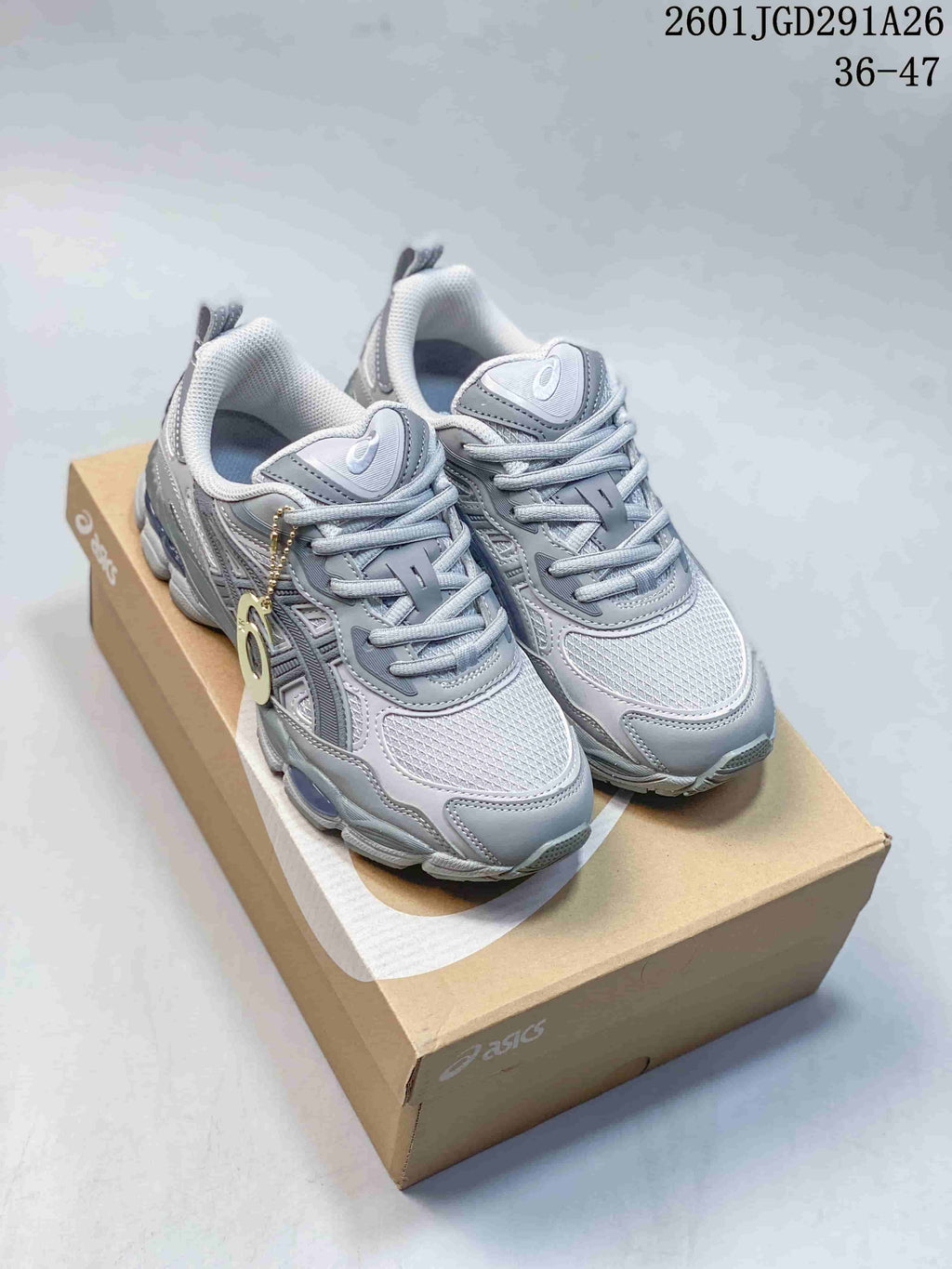 Pair of gray ASICS GEL-NYC RGD sneakers displayed on a shoebox, with the size range 36–47 visible in the upper right.