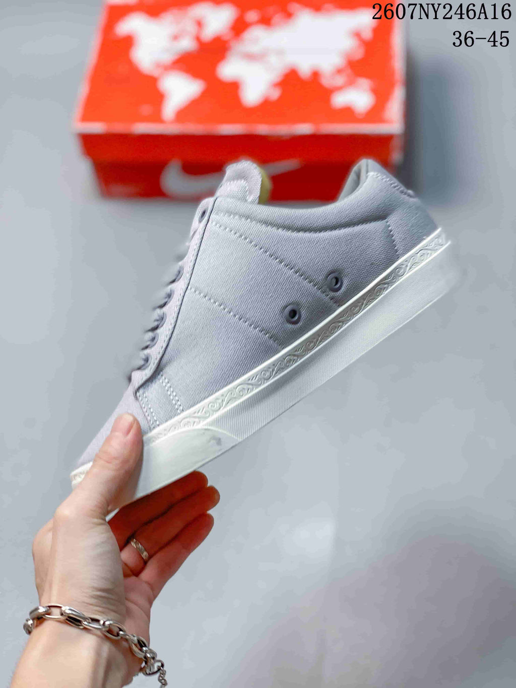 Side view of the gray low-top sneaker highlighting the stitched panels, eyelets, white outsole, and patterned midsole strip.