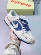 Close-up of a white low-top sneaker with blue panels, contrasting laces, and red tongue branding.